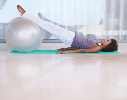Strengthening her core. Shot of an attractive young woman doing pilates with an exercise ball.