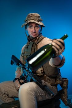 a drunk army soldier in military clothes with a bottle of alcohol in his hand offers to drink
