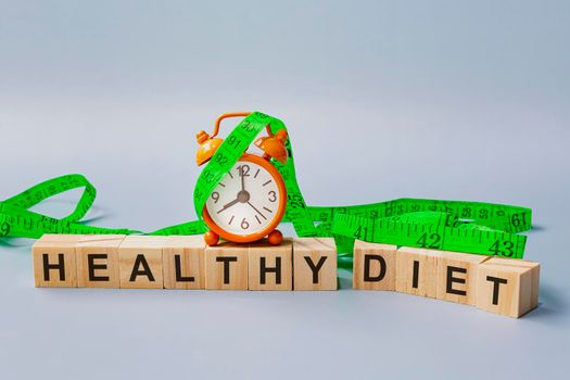 Healthy diet text on wooden block cube with measure tap and orange clock.