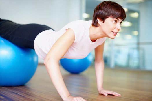 Push ups. Woman doing push ups using pilates ball during a workout session.