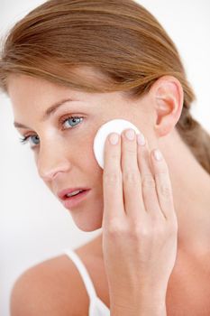 Skincare and beauty. A lovely young woman applying makeup to her cheek with a cotton pad.