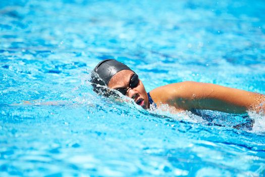 Training to be the best. Female swimmer making her way through a swimming pool stroke by stroke.