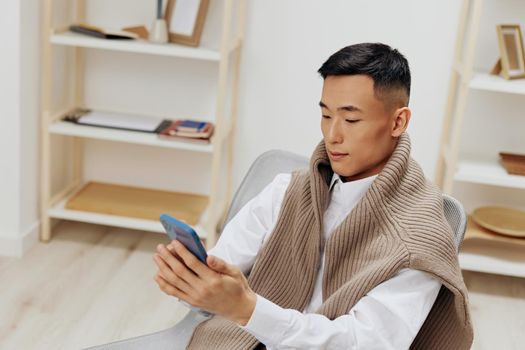 teenager sitting in a chair in a room with phone on his lap Lifestyle