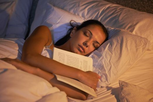 She fell asleep reading again. Shot of an attractive young woman sleeping holding book.