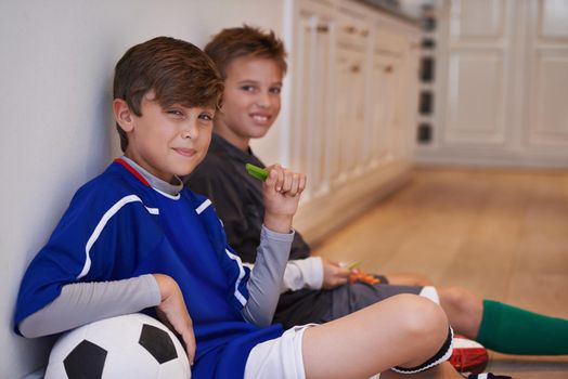 Boys will be boys. Shot of two little boys sitting with a soccer ball and having healthy snacks.