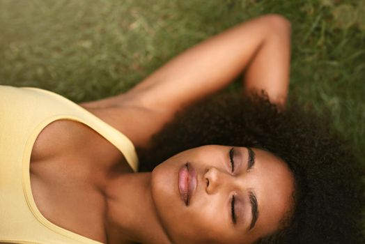 Absolute bliss.... Shot of a relaxed young woman lying on the grass with her eyes closed.