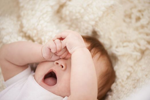 Its definitely nap time. Shot of an adorable baby yawning.