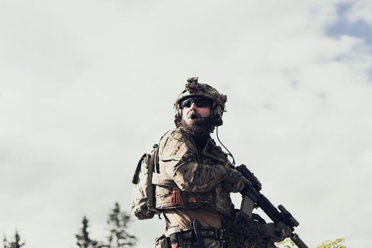 War concept. A bearded soldier in a special forces uniform fighting an enemy in a forest area. Selective focus