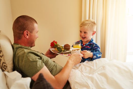 Serving breakfast to the best Dad ever. Cropped shot of a little boy serving breakfast in bed to his father at home.