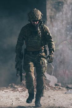 A bearded soldier in a special forces uniform walks through an abandoned building after a successful mission. Selection focus