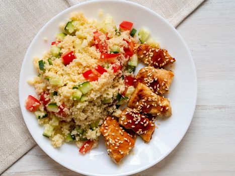 Turkey meat, fried, with teriyaki sauce and sesame seeds. Couscous with vegetables. Selective focus, day natural light