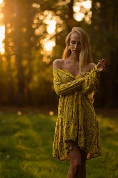 Blond woman resting in forest at sunset