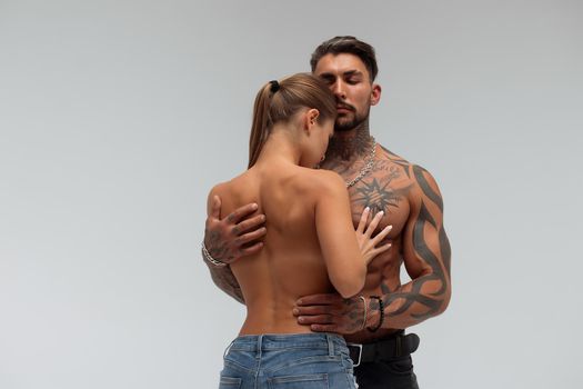 Muscular man hugging topless woman