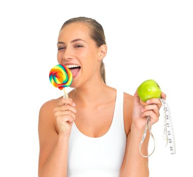I thought Id reward myself.... Portrait of a sporty young woman licking a lollipop while holding an apple.