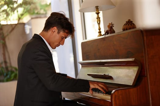 Losing himself in the music. Shot of a handsome young man playing the piano at home.