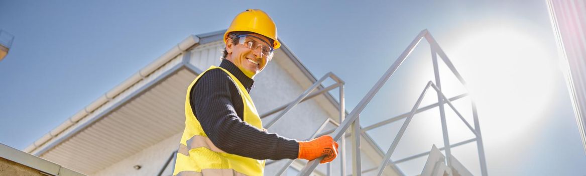 Cheerful male engineer climbing stairs at factory