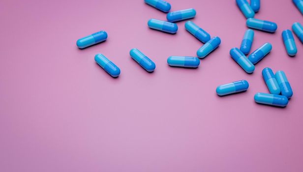 Top view capsule pills on pink background. Prescription drugs. Blue capsule pills. Pharmaceutical industry. Medicament and pharmacology. Drug development and new drug research. Capsule pills industry.