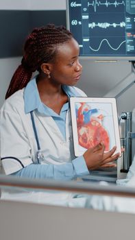 Medic pointing at tablet with cardiology image on display