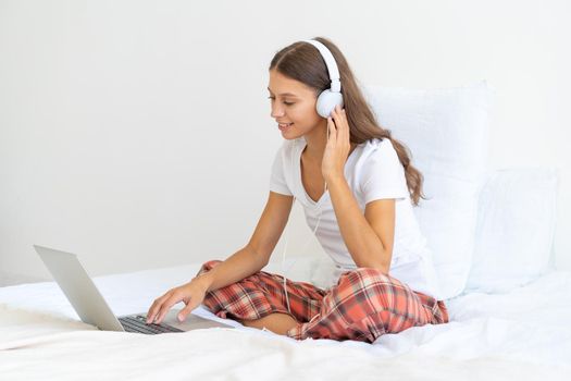 Young woman in headphones studying online, working from home using laptop