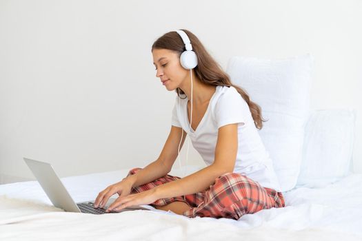 Young woman in headphones studying online, working from home using laptop