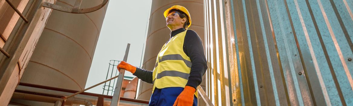 Cheerful male worker standing on stairs at factory