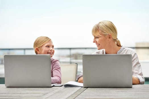 Just like her mom. Shot of a young girl and her mother using laptops side by side.