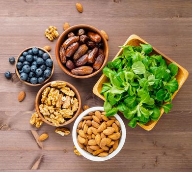 Healthy vegan food - dry fruits, greens, nuts, berry. Superfoods on brown wooden background, top view