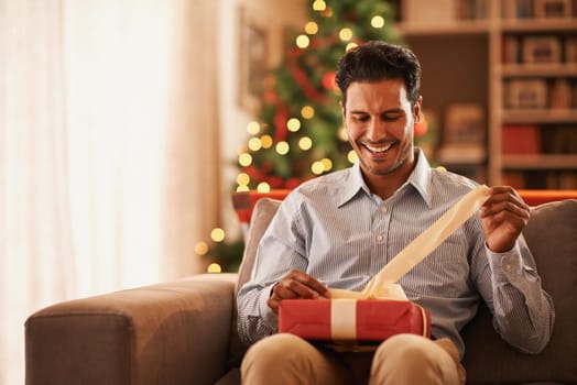 Feeling like a kid on christmas. Shot of a handsome young man opening a christmas present.
