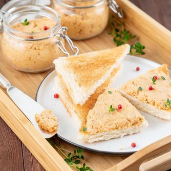 Fresh homemade chicken pate on toasted bread on tray over rustic background, side view
