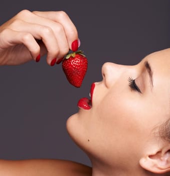 Sensuous strawberries. Closeup portrait of a beautiful young woman with strawberry in her mouth.
