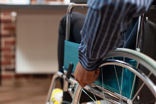 Focus on startup employee hand holding rim of wheelchair wheel to move around