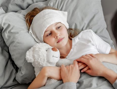 Child girl with teddy bear toy in the bed
