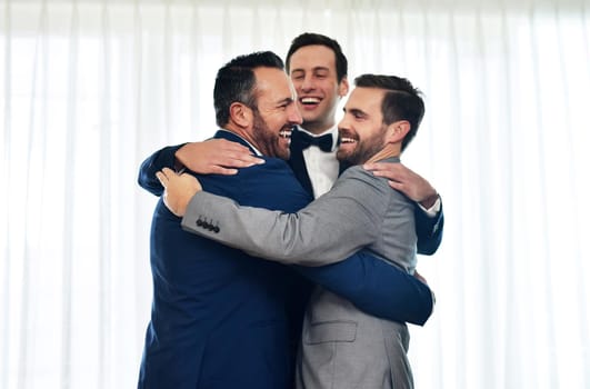 Blessed to have them with me on this special day. Shot of two groomsmen hugging and celebrating with the bridegroom on his wedding way.