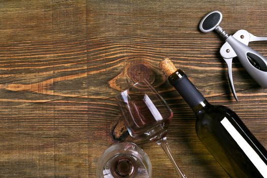Bottle and two glasses of wine on wooden background from top view