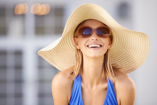 Poolside happiness. A blonde woman wearing a sun hat and smiling at the camera.