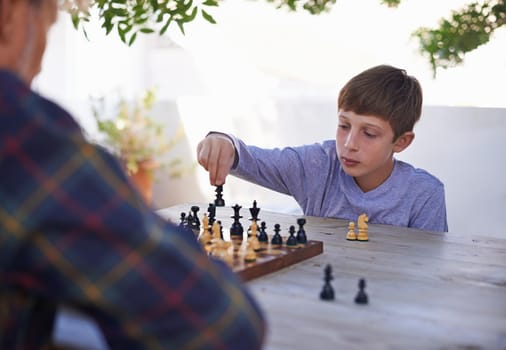 His granddad is a worthy adversary. Shot of a young boy playing chess with his grandfather.