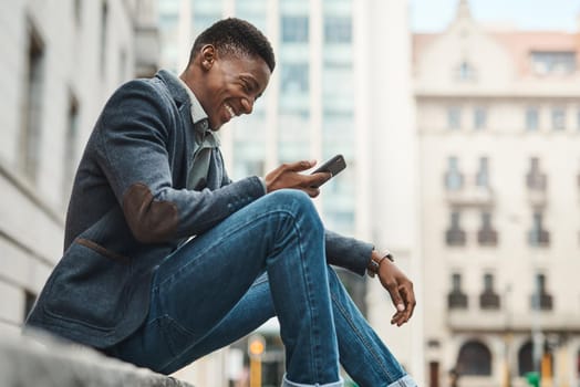Welcome to Avenue Success. Shot of a young businessman sitting on the curb and using a smartphone against an urban background.