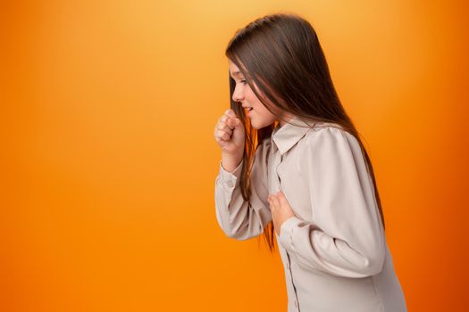 Teen girl wearing casual clothes feeling unwell and coughing against orange background