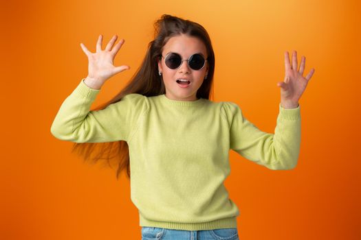 Funny caucasian teen girl in eyeglasses isolated on orange background