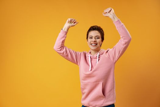 Surprised happy beautiful woman looking in excitement over yellow background