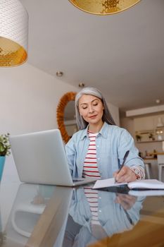 Woman working on notebook and taking notes at home