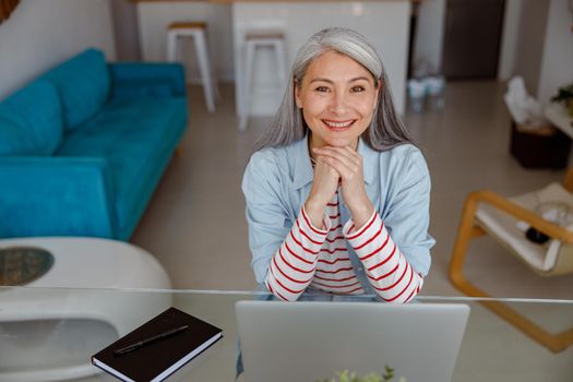 Cheerful woman sitting at the table with laptop at home