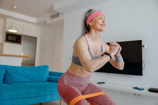 Cheerful woman doing exercise with resistance band at home