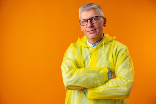 Mature man wearing raincoat over yellow background