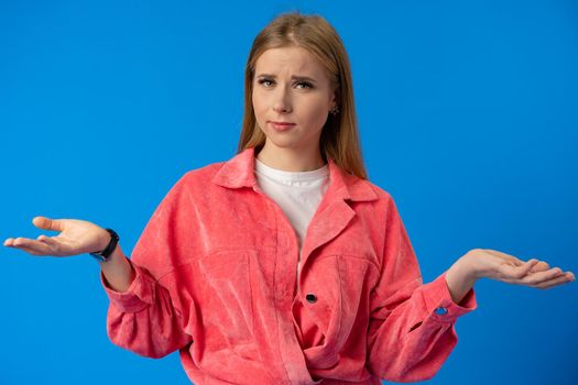 Portrait of a beautiful confused young girl on blue background