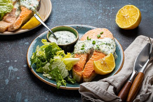 Healthy food meal cooked grilled salmon steak with white dill sauce and green salad leafs