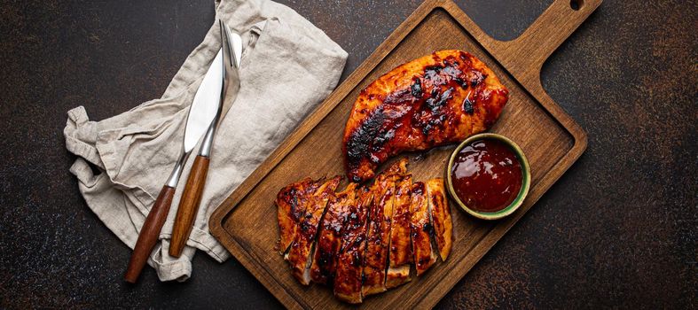 Grilled turkey or chicken fillet with red sauce served and sliced on wooden cutting board