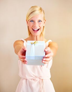 Surprise - its for you. Portrait of a young woman holding out a gift box and smiling.