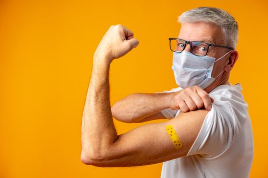 Senior man against yellow background recieved corona virus vaccination