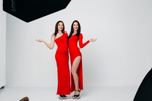 Two sexy sisters twins in red dresses.